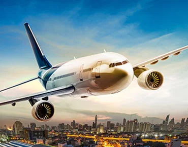 Canbeck cargo airplane flying over city skyline at sunset